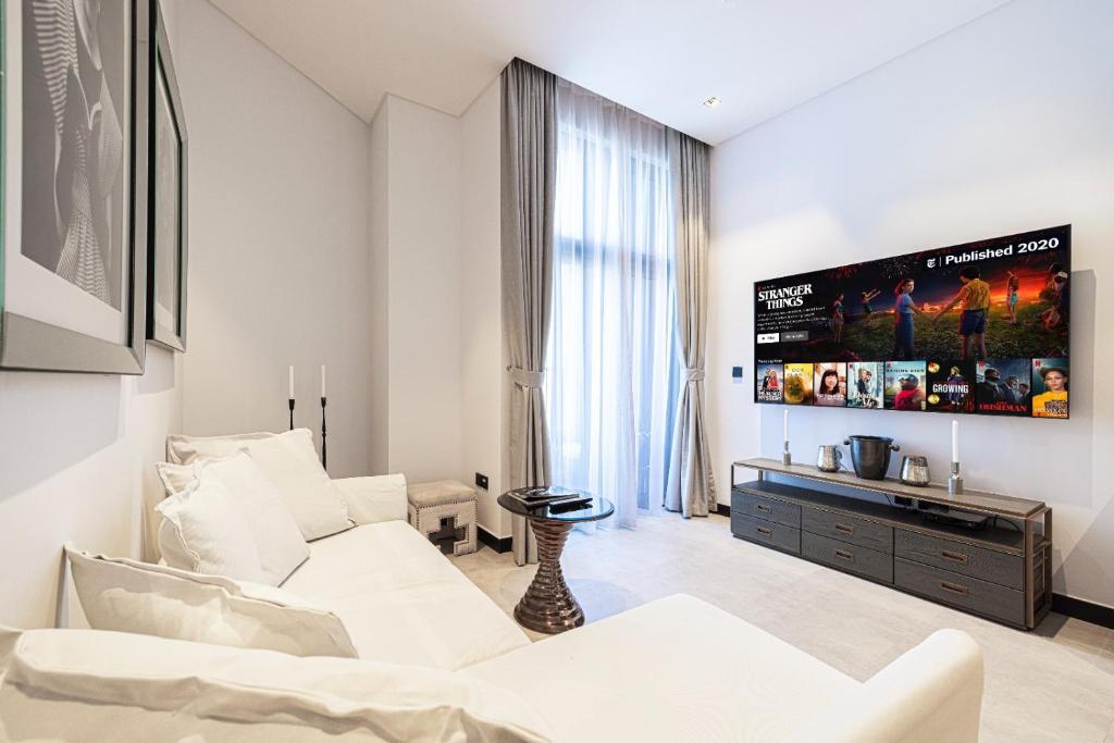 Bright open-plan living room with white sofa, wall-mounted TV and floor-to-ceiling window