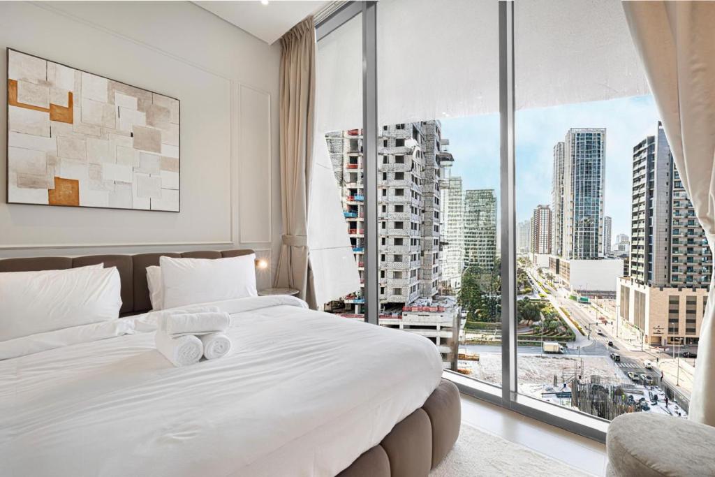 Bedroom with white bedding and floor-to-ceiling windows over the Dubai skyline