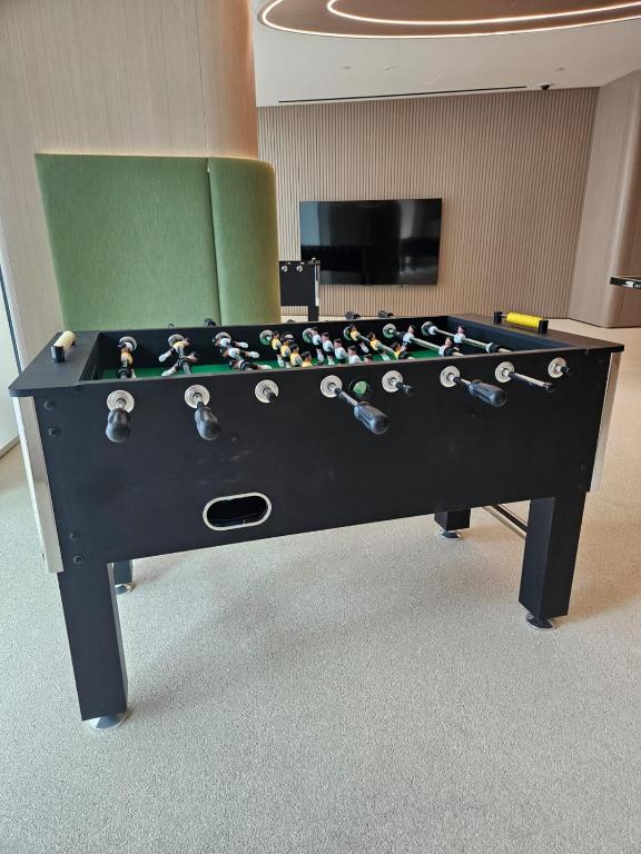 Foosball table in a lounge with green seating and a wall-mounted TV