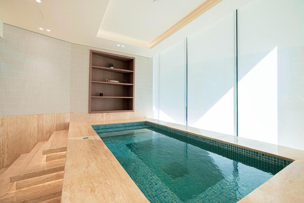 Indoor plunge pool finished in green mosaic tiles with a stone surround