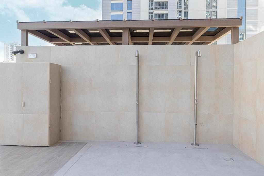 Stone-walled outdoor shower area beneath a wooden pergola